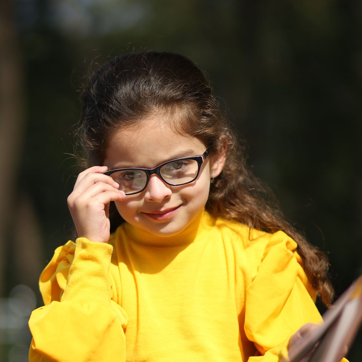A smiling girl in glasses sitting with her books