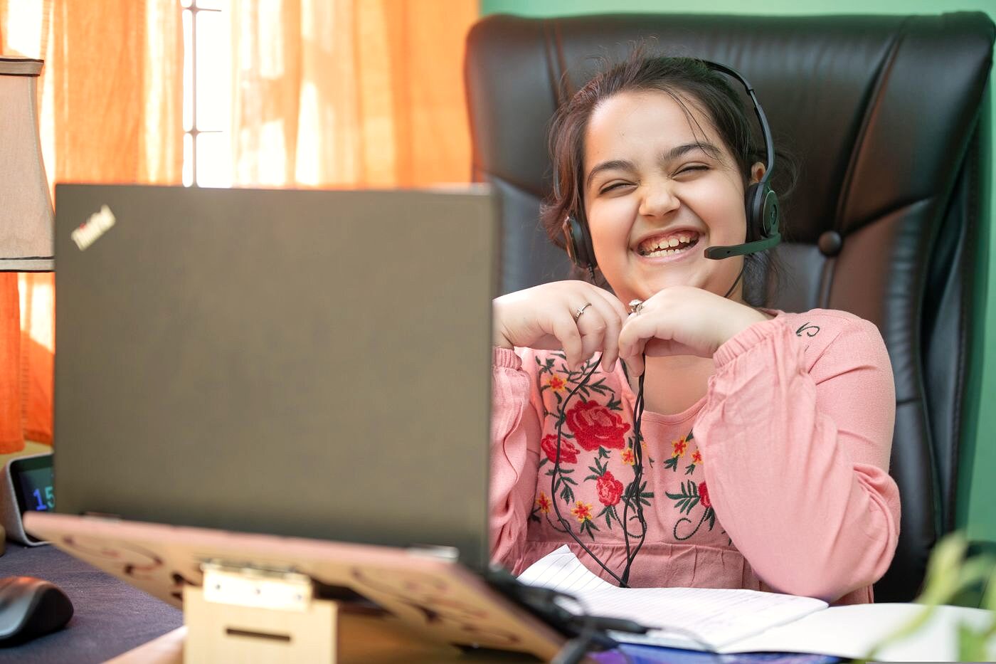 A smiling girl in a headset enjoying her online abacus class from home